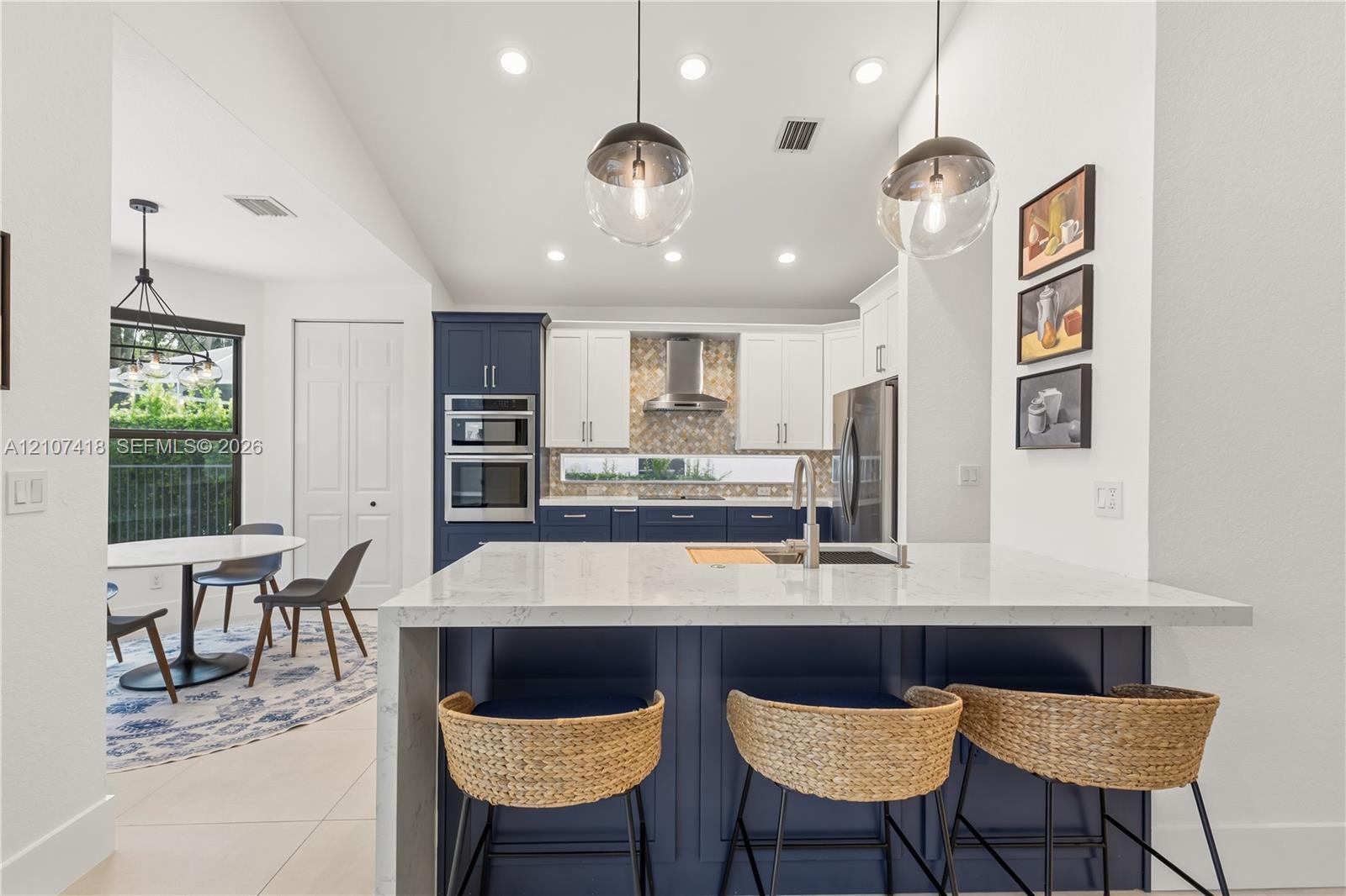 Kitchen featuring a central island with a solid surface countertop, contrasting navy and white cabinetry, a built-in double wall oven, patterned tile 