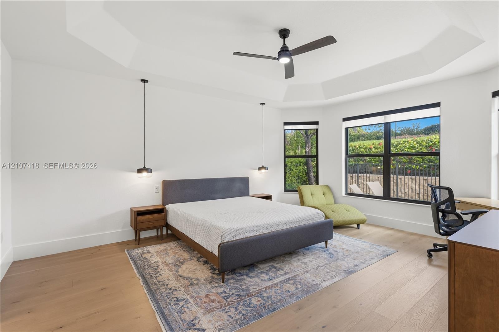 Tray ceiling, wood-finish flooring, matte black ceiling fan, and black-framed windows