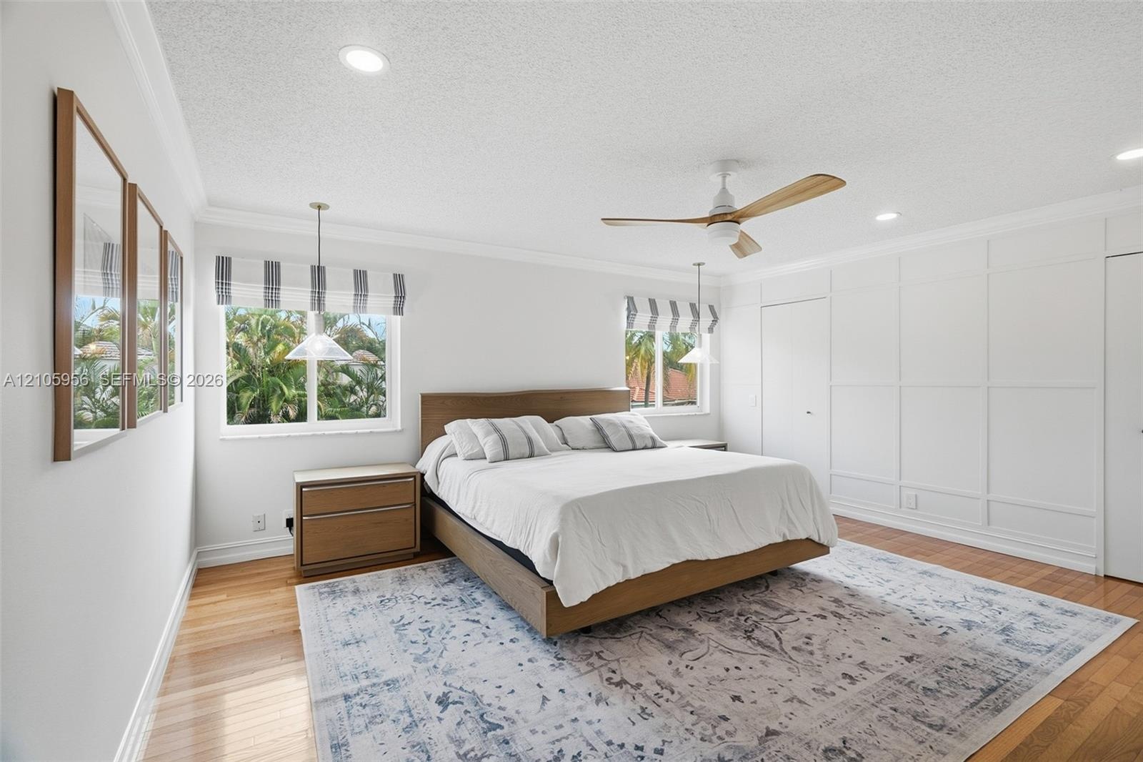 Interior space featuring wood-finish flooring, decorative wall paneling, crown molding, a central ceiling fan with wood-finish blades, and recessed li