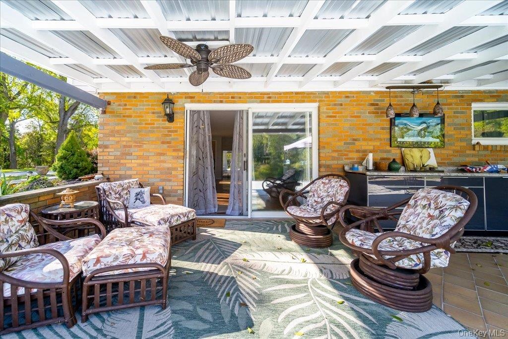 Entertain out in this covered side-patio featuring outdoor -kitchen cabinetry overlooking the pond and expansive grounds!