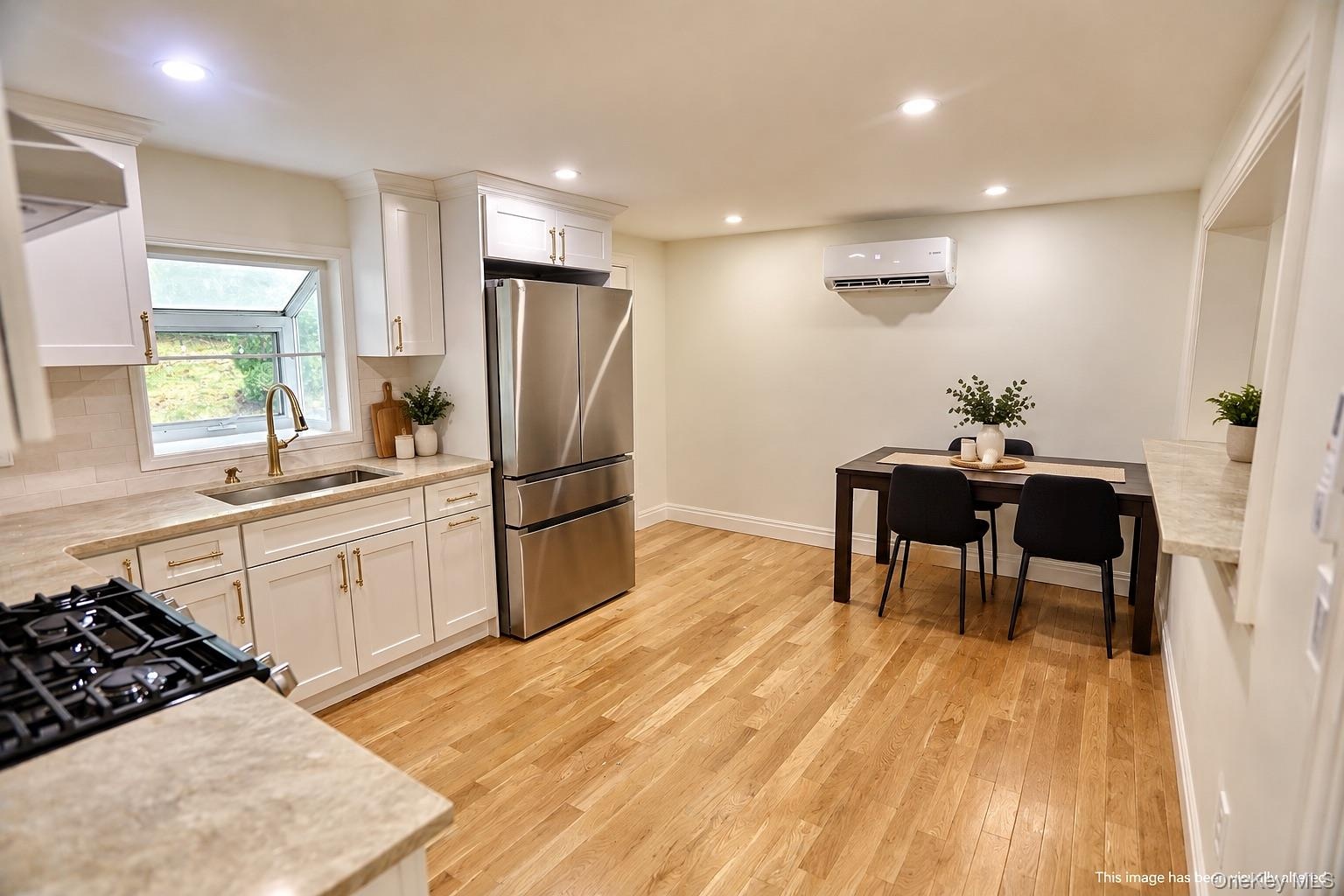 Kitchen featuring white shaker-style cabinetry, stainless steel appliances, recessed lighting, and wood-finish flooring