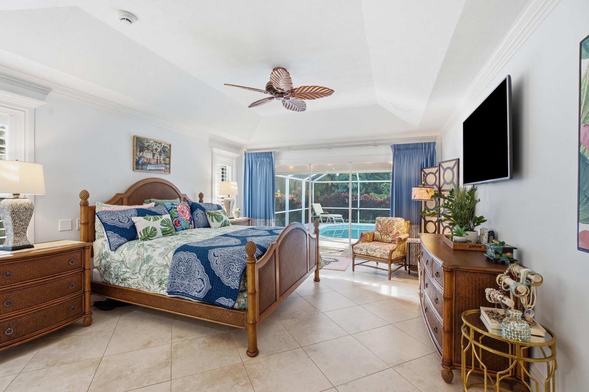 Tray ceiling, neutral tile flooring, ceiling fan with palm-style blades, and floor-to-ceiling glass sliding doors with screen enclosure