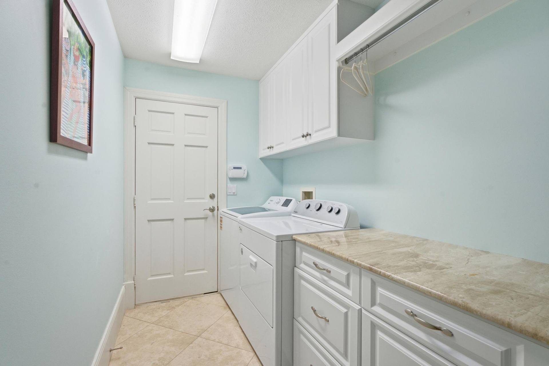 Laundry area featuring tile flooring, built-in white cabinetry, stone-finish countertops, and an integrated hanging rod