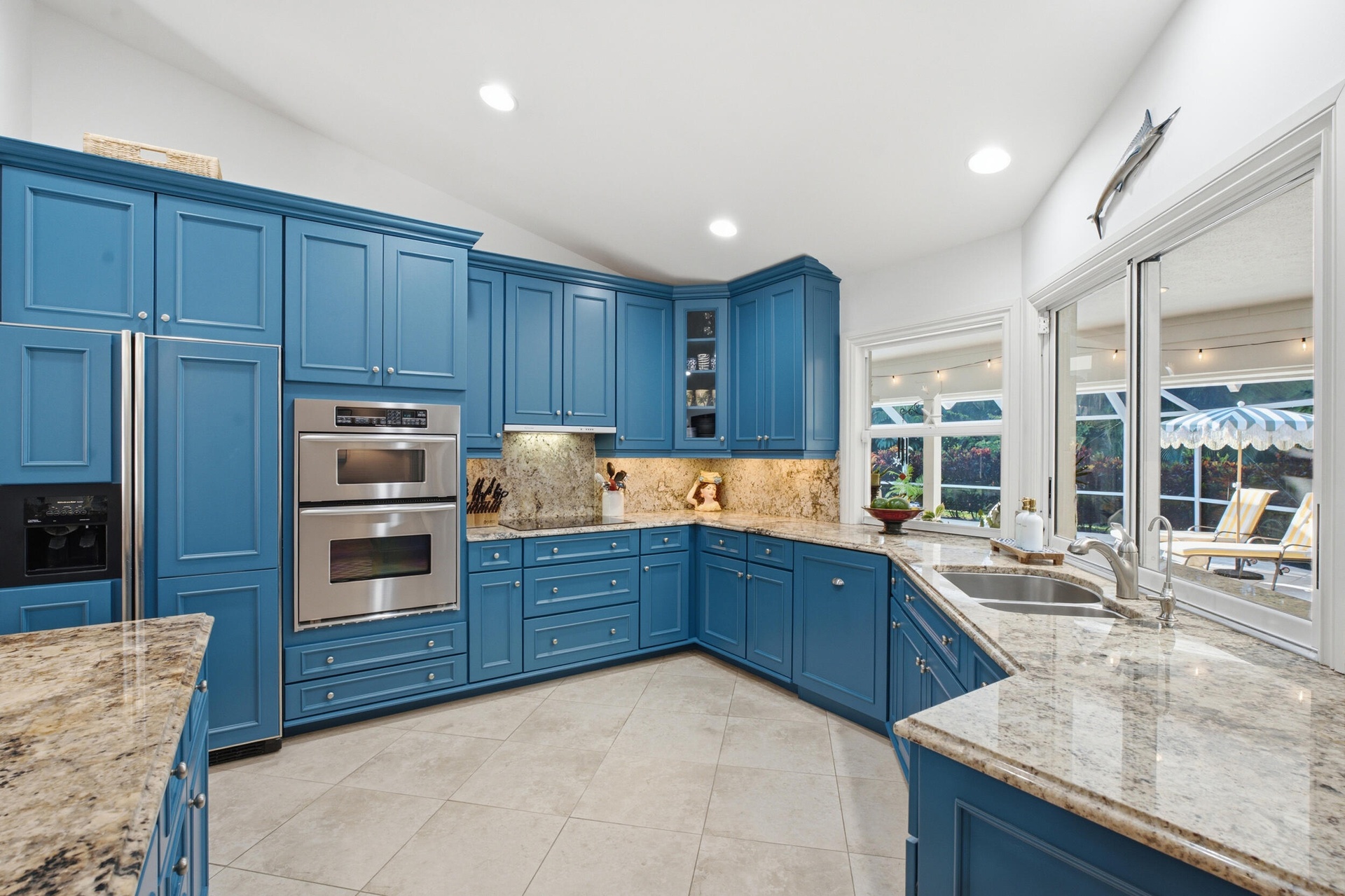 Kitchen featuring blue cabinetry, stone countertops, stainless steel double wall oven, tile flooring, and windows with recessed lighting