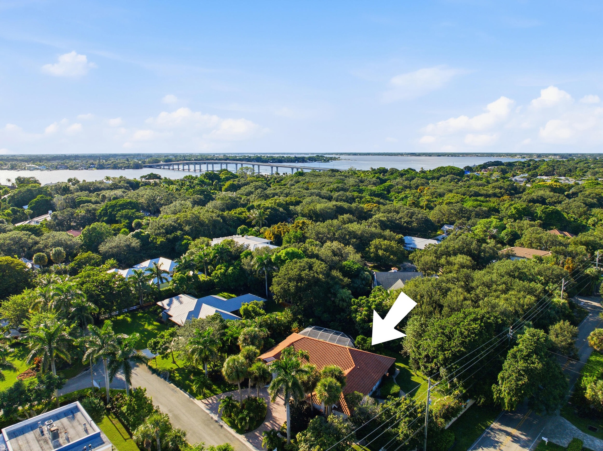 Aerial perspective featuring a tile roof, screened lanai enclosure, and mature landscaping