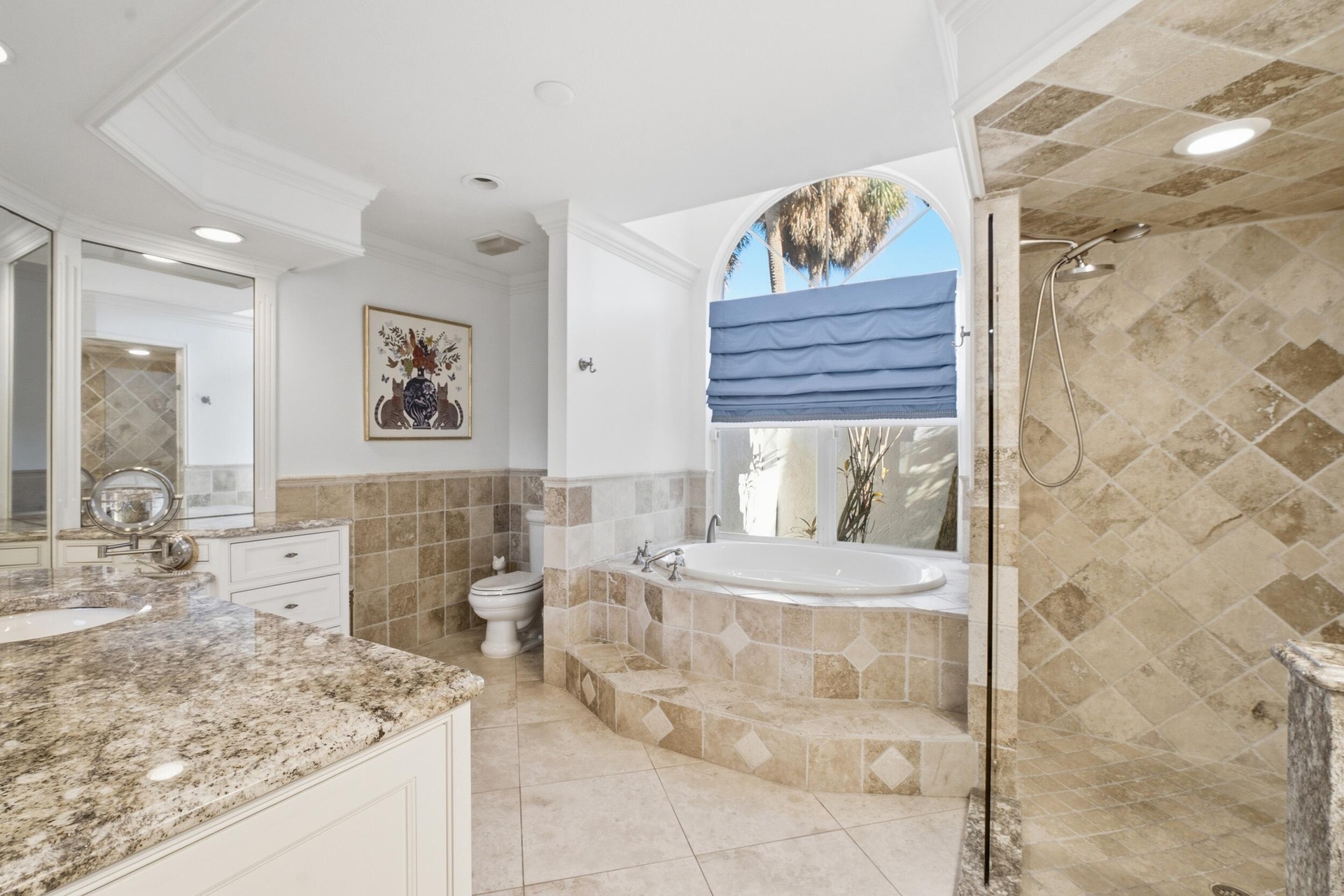 Bathroom featuring a jetted soaking tub set within a stone-tiled surround, a walk-in shower with diamond-pattern stone tile, a stone-surfaced vanity, 