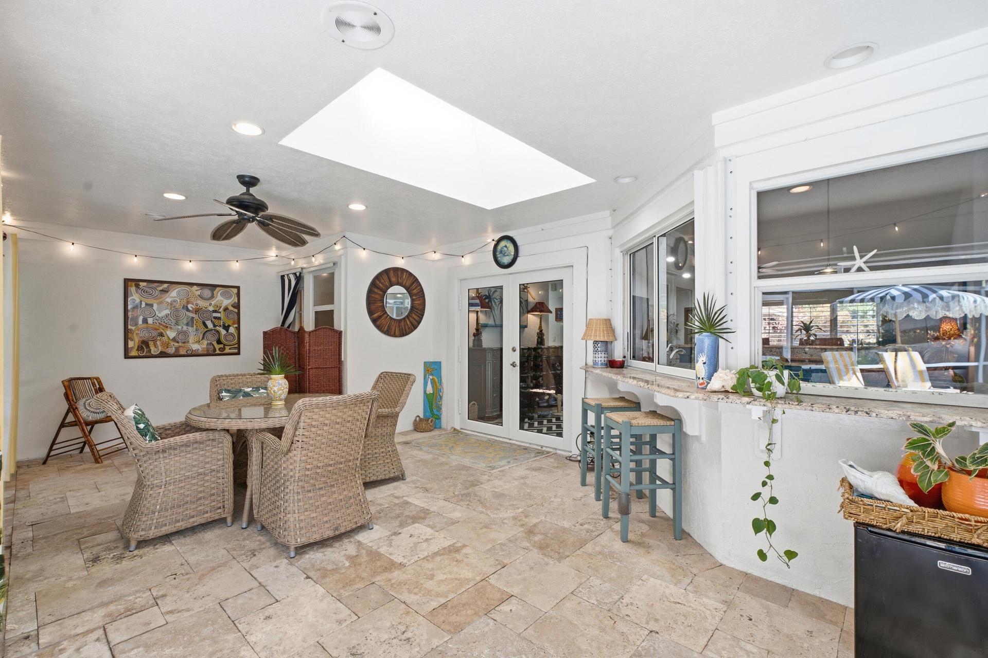 Covered patio featuring stone-tile flooring, a large skylight, recessed lighting, and a built-in stone-surfaced breakfast bar