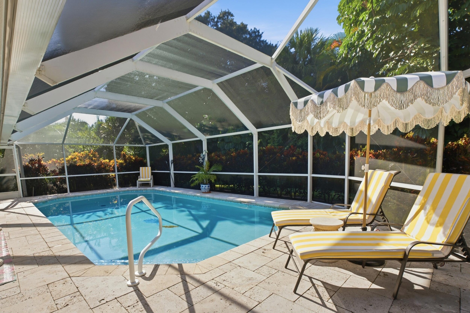 Screened-in pool enclosure featuring a stone-tile deck, built-in pool ladder, and expansive exterior landscape