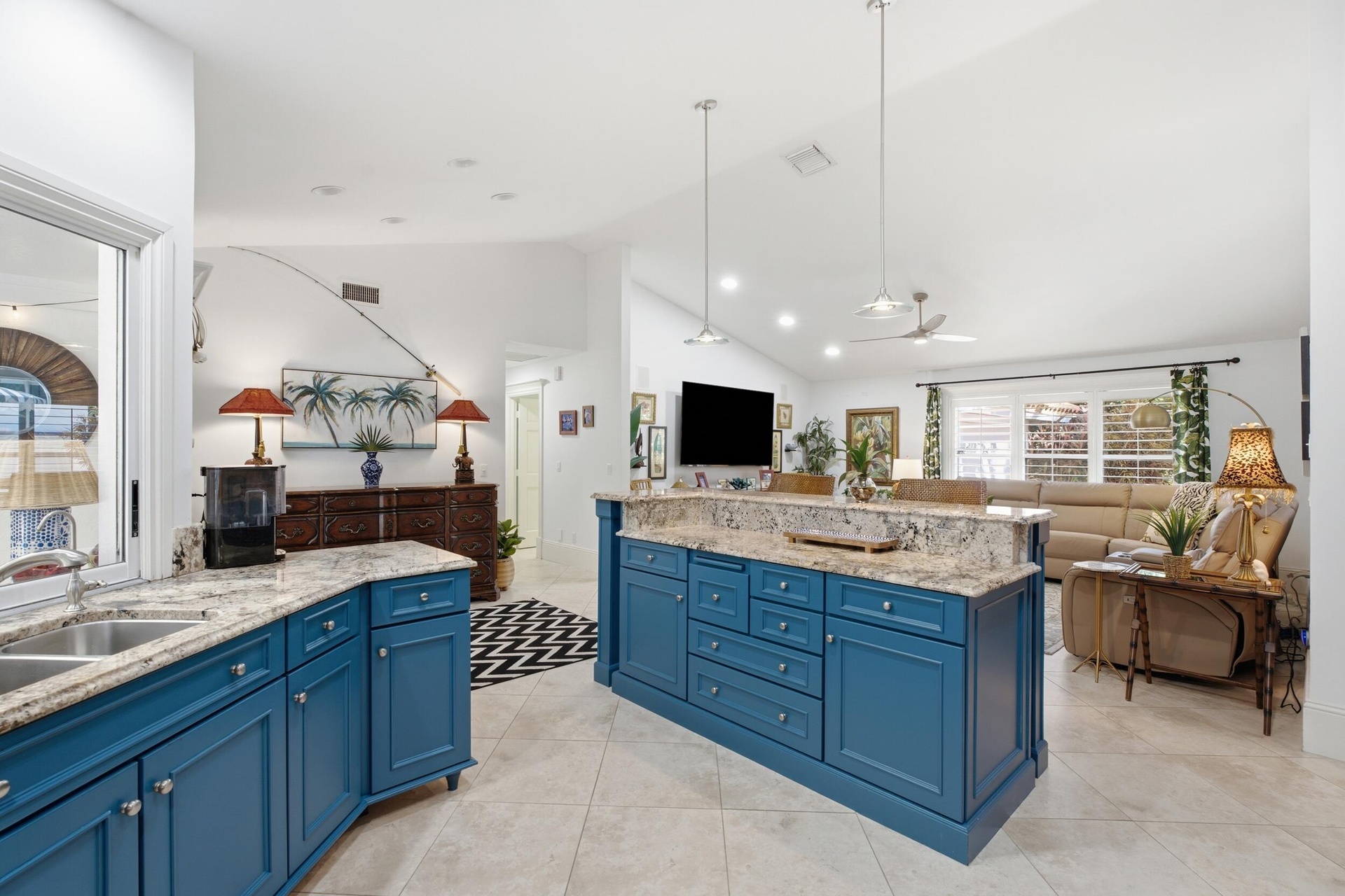 Kitchen featuring blue cabinetry, stone countertops, a large center island, tile flooring, and vaulted ceilings