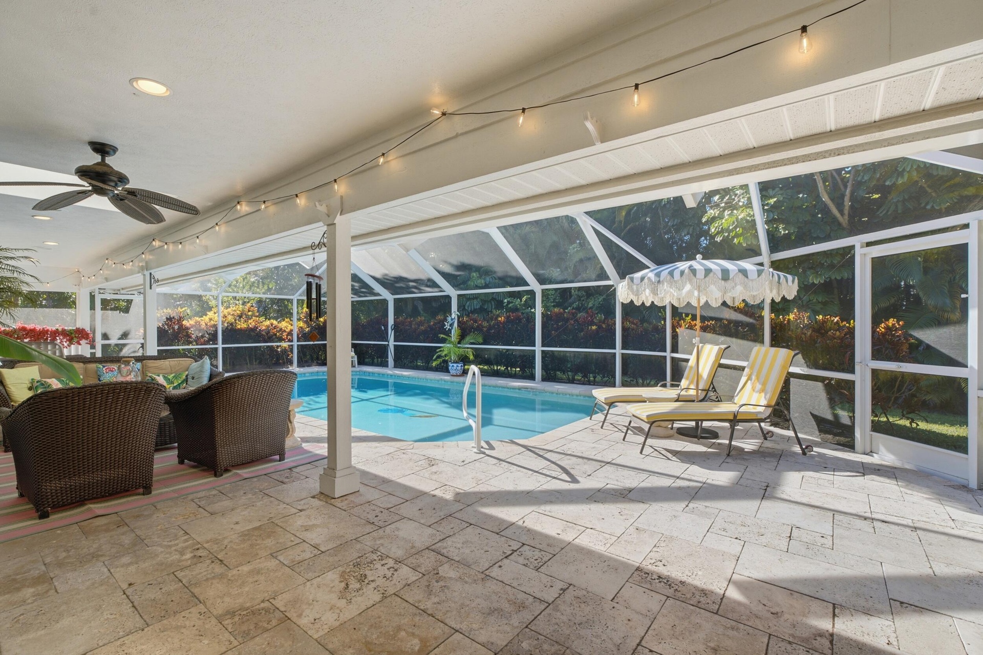 Covered outdoor patio with natural stone flooring, ceiling fan, recessed lighting, and a screened-in enclosure featuring a swimming pool