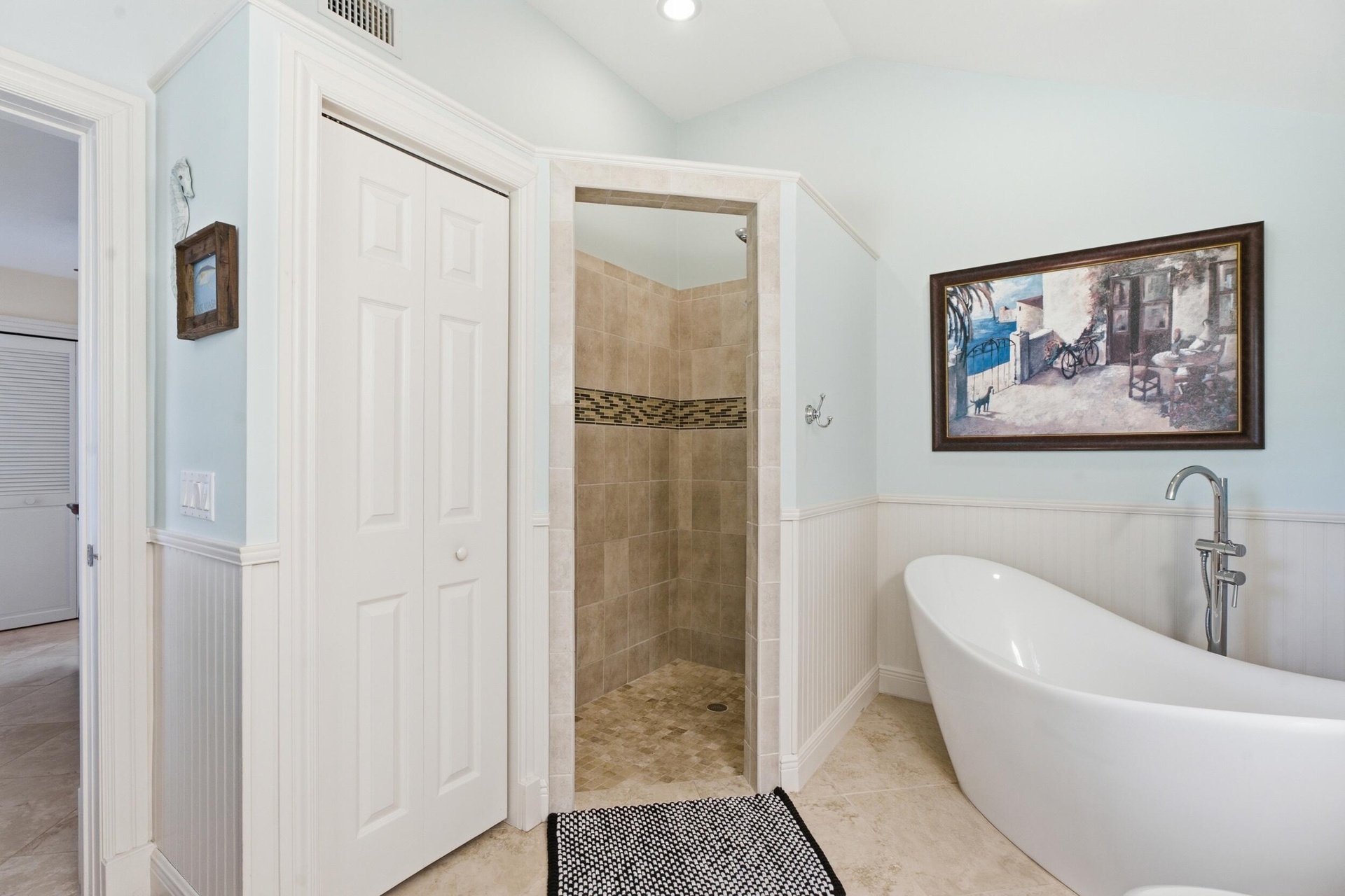 Freestanding soaking tub with a floor-mounted faucet, walk-in shower with tiled surround, beadboard wainscoting, and recessed lighting