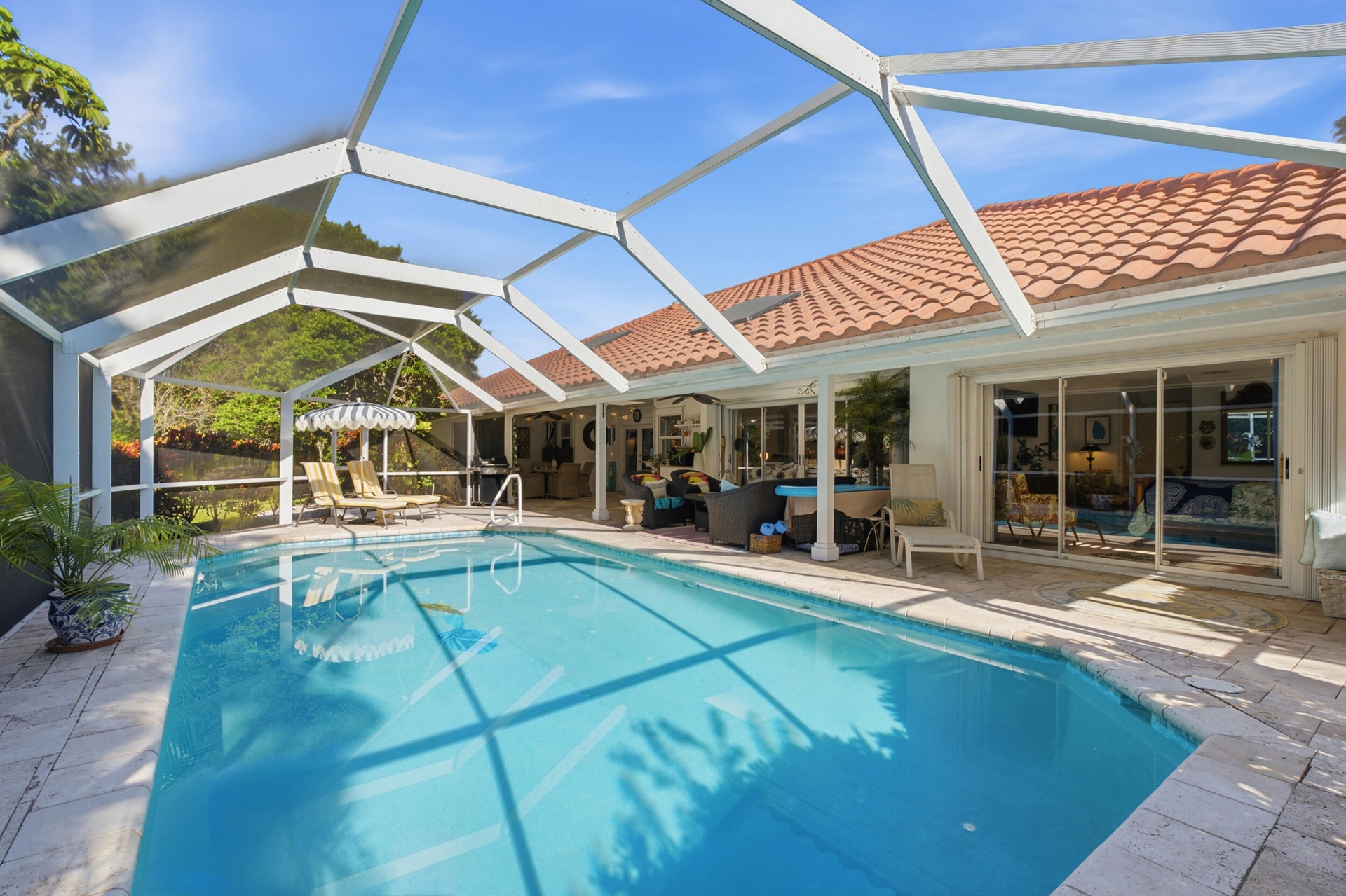 Screen-enclosed swimming pool featuring a paver stone deck, tile roof, and expansive sliding glass door entry