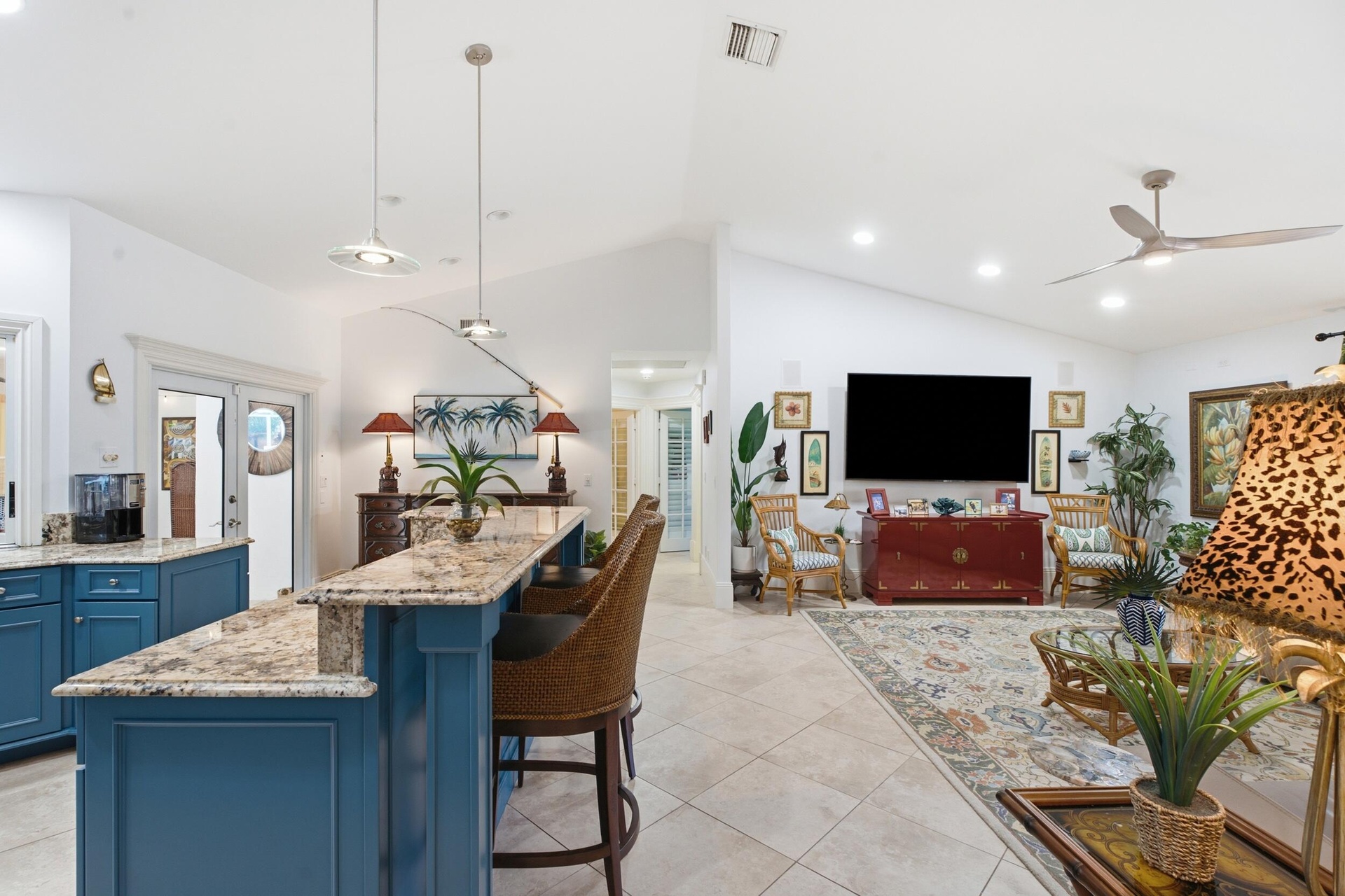 Vaulted ceilings featuring recessed lighting, a kitchen island with stone countertops, blue cabinetry, tile flooring, and a ceiling fan