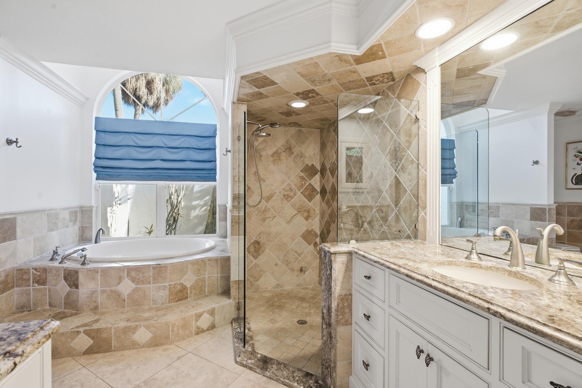 Spa-inspired primary bathroom featuring a soaking tub with tile surround, walk-in shower with glass enclosure and stone-look tile walls, dual vanity w