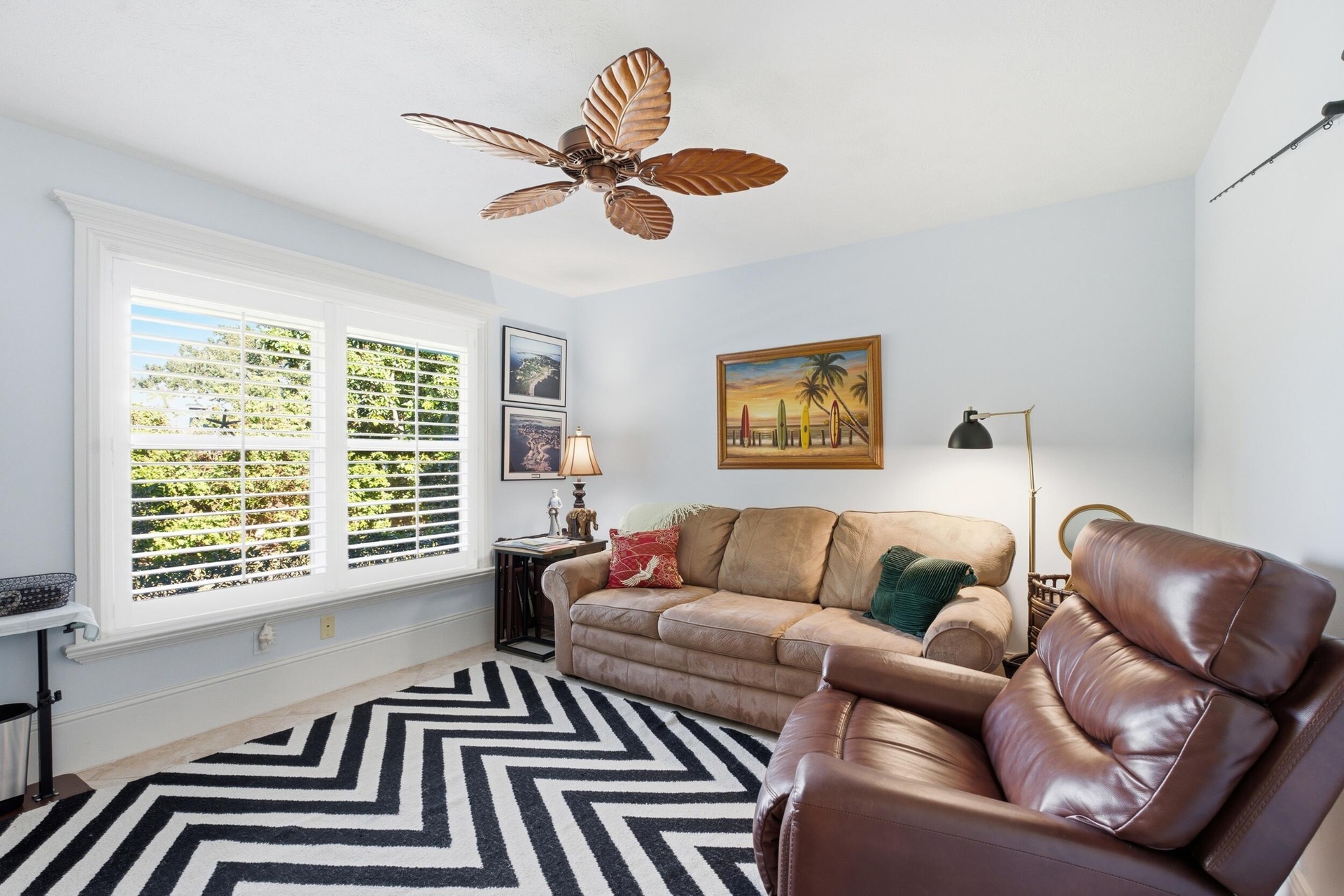 Interior space featuring a palm-leaf blade ceiling fan and double-pane windows with plantation-style shutters