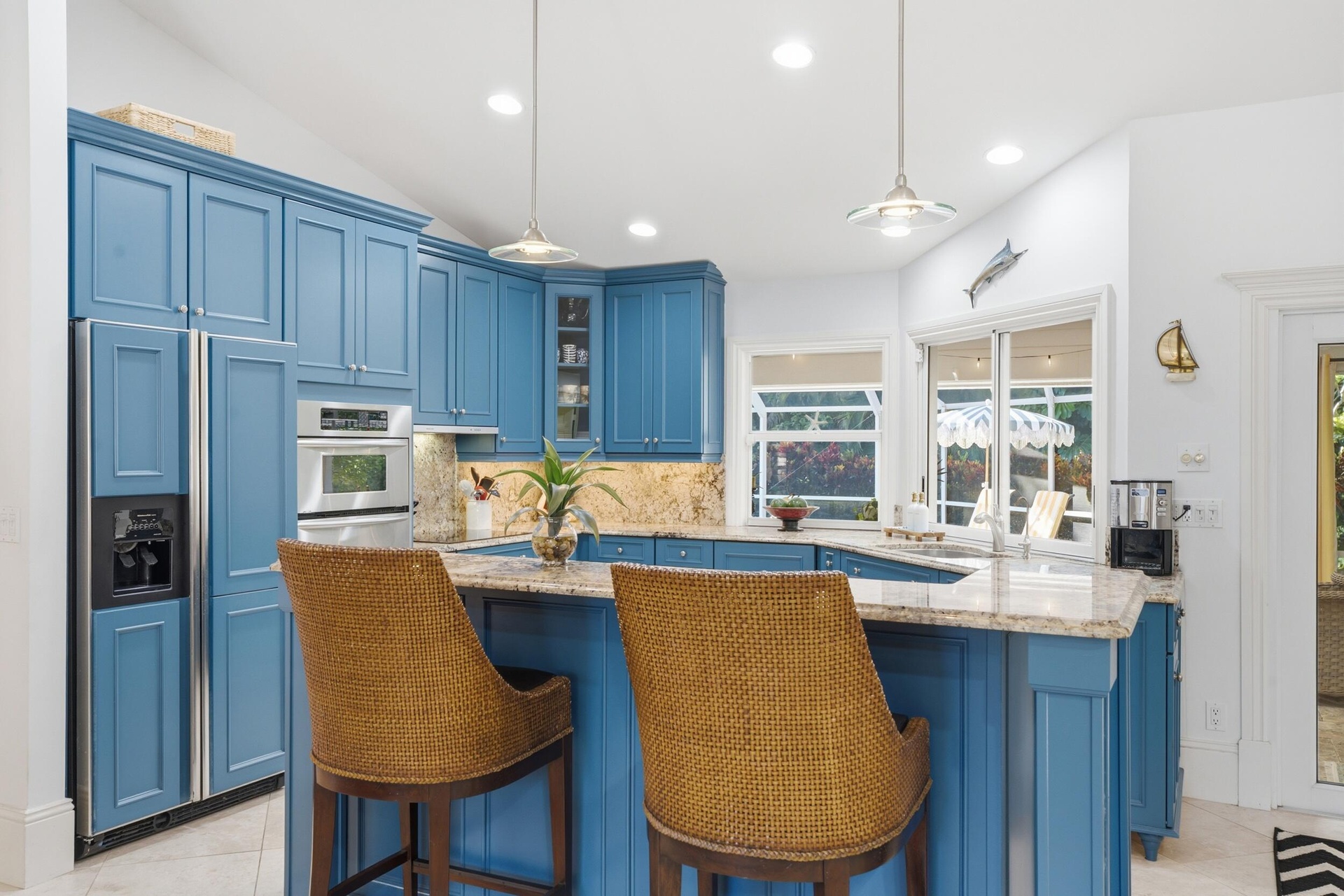 Kitchen featuring blue custom cabinetry, stone countertops, stainless steel wall-mounted oven, and dual pendant lighting
