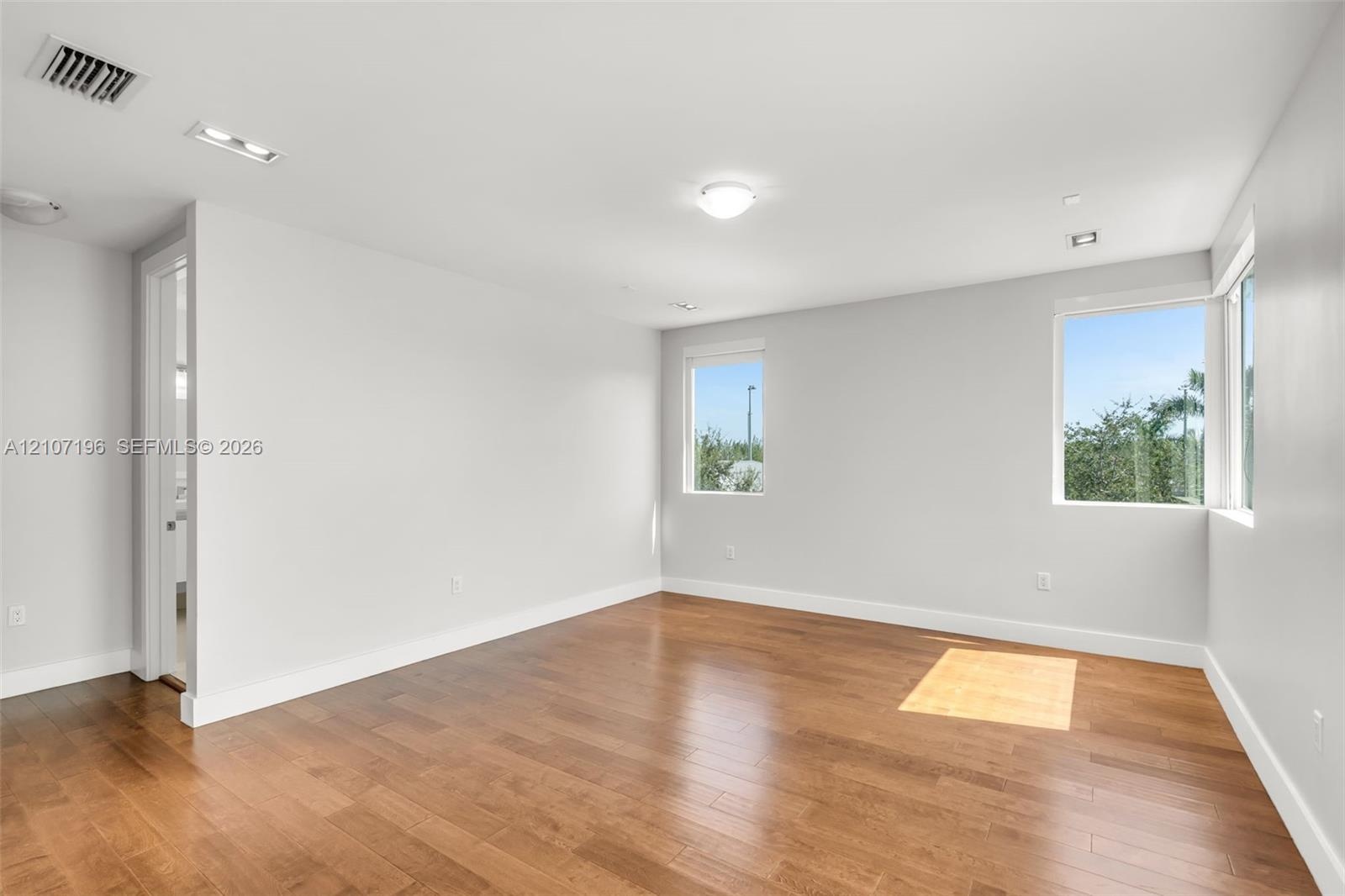 Interior space featuring wood-finish flooring, recessed ceiling lighting, and multiple windows