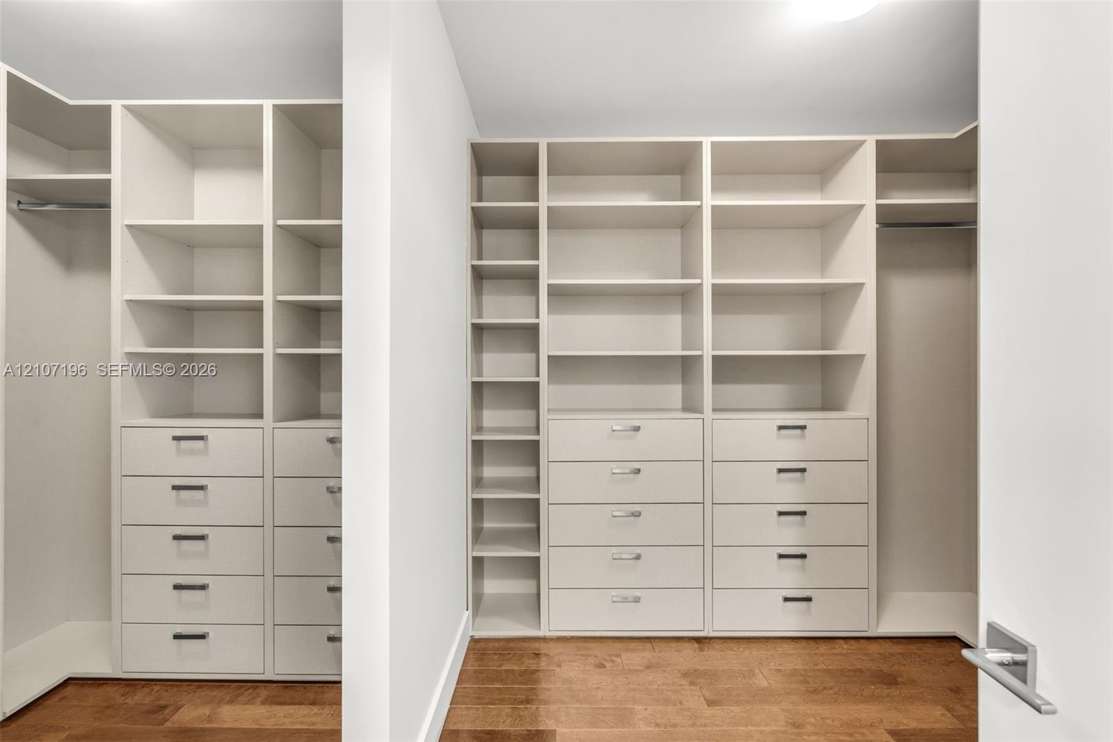 Custom-built closet storage system featuring floor-to-ceiling shelving, integrated drawers with brushed hardware, dedicated hanging rods, and wood-fin
