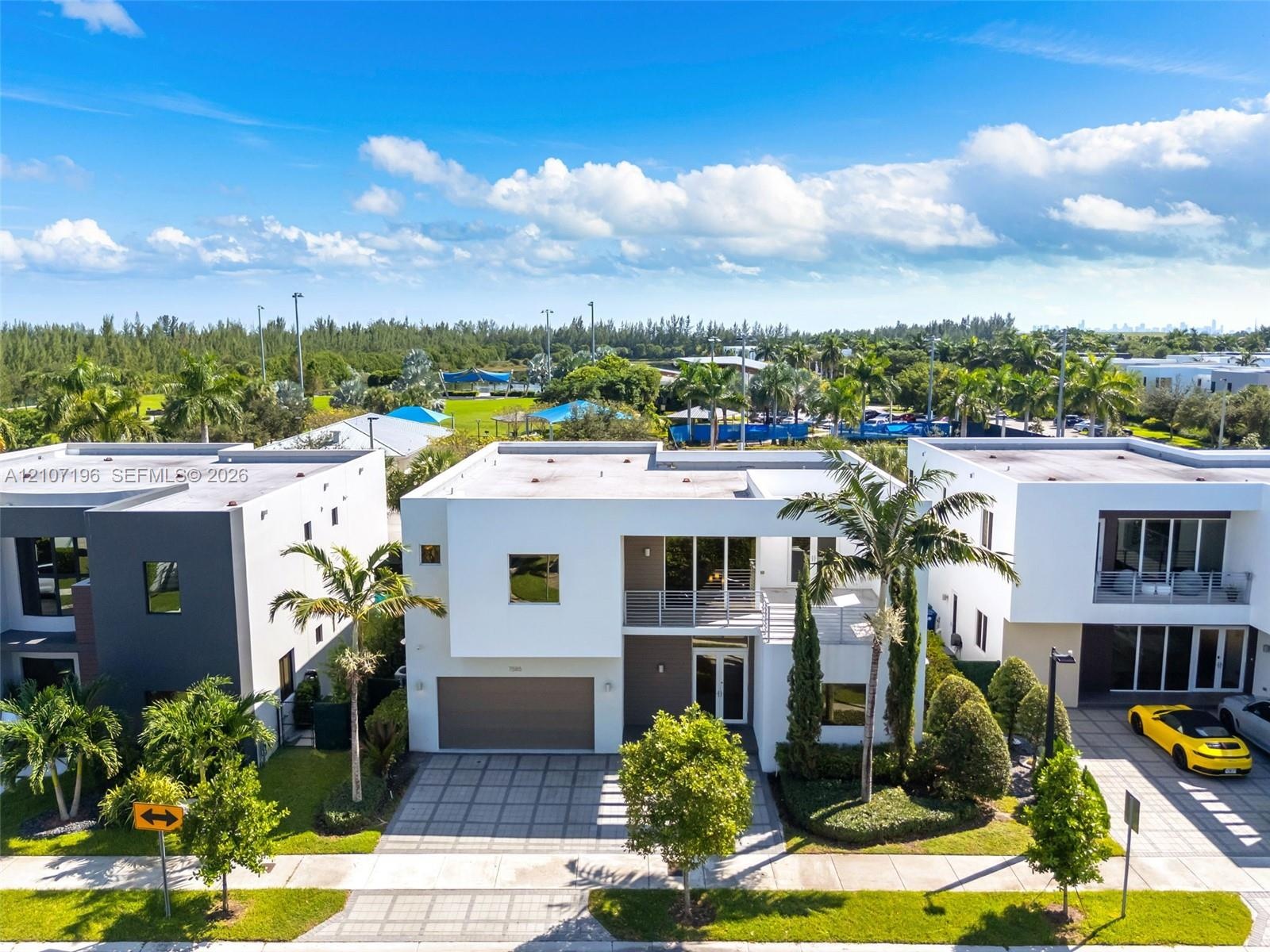 Modern two-story architectural exterior featuring a flat roofline, grid-patterned concrete paver driveway, attached two-car garage, second-level balco