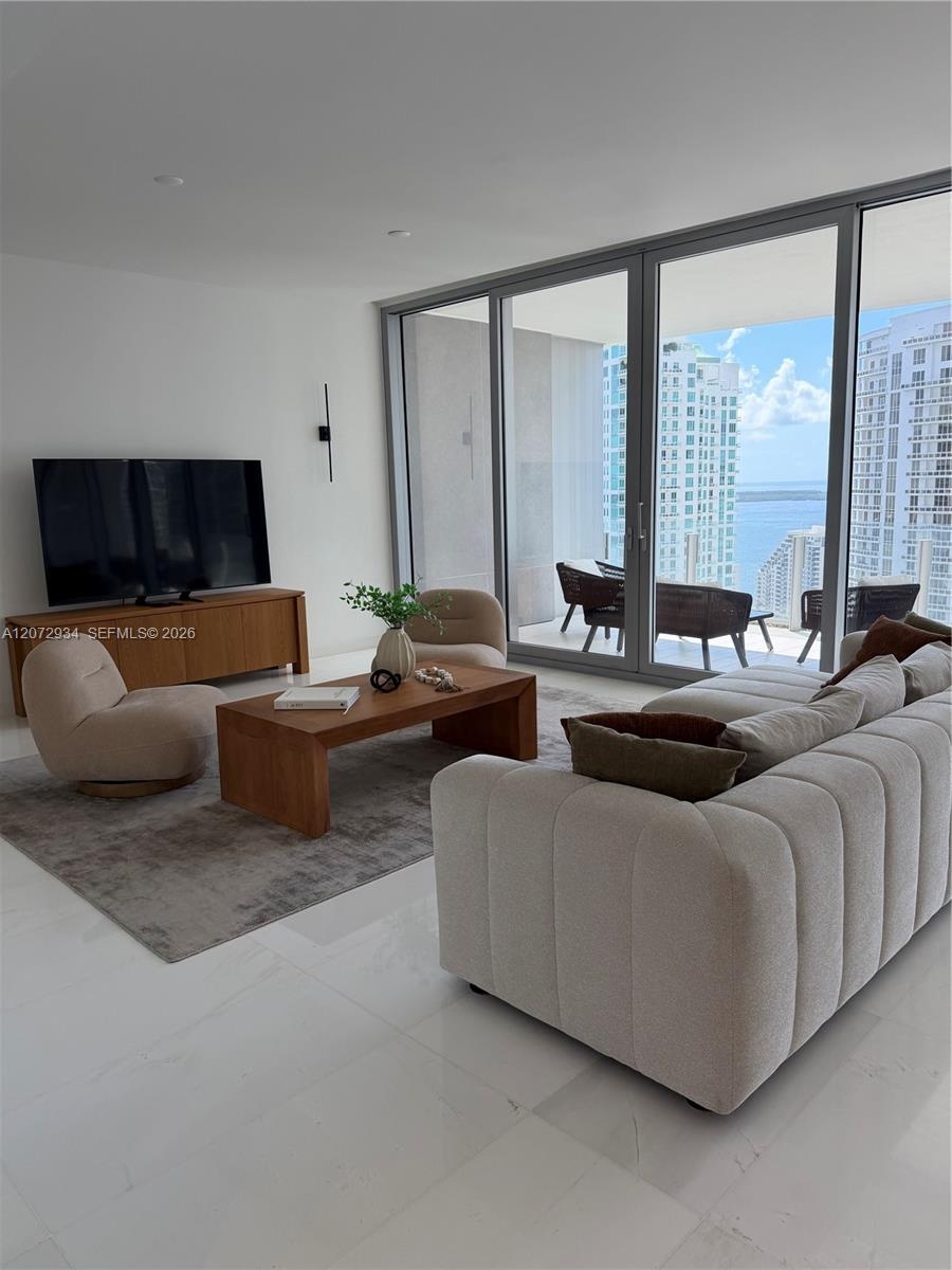 Floor-to-ceiling glass panel doors, polished stone-finish flooring, recessed lighting, and a private balcony