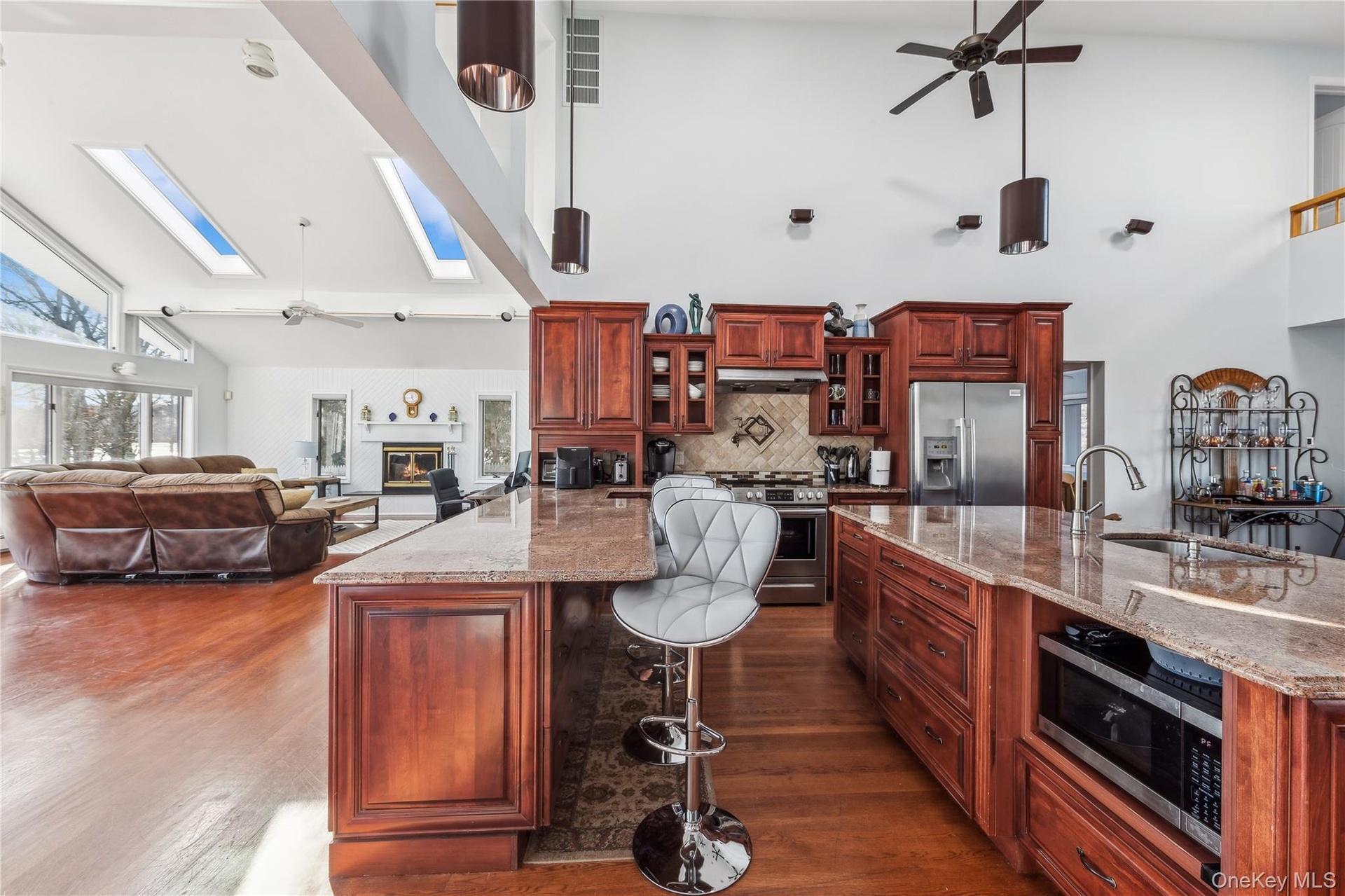 Kitchen featuring sink, a skylight, stainless steel appliances, and light stone countertops