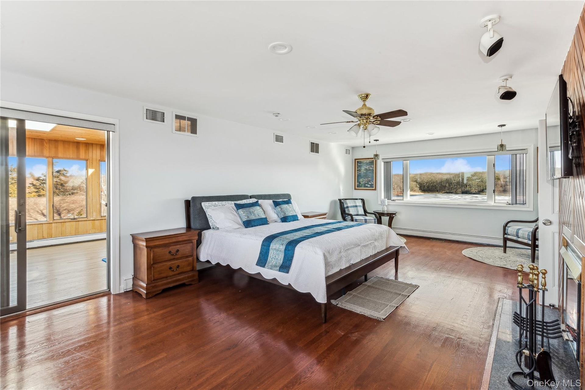 Bedroom with ceiling fan, wood-type flooring, and a baseboard heating unit