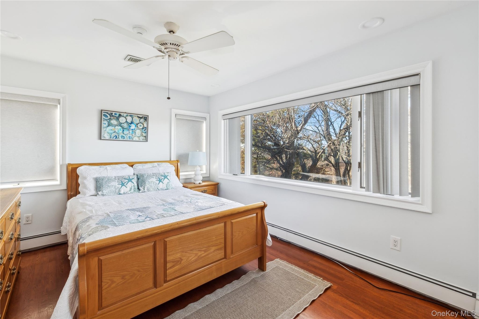 Bedroom with dark hardwood / wood-style flooring, a baseboard heating unit, and ceiling fan