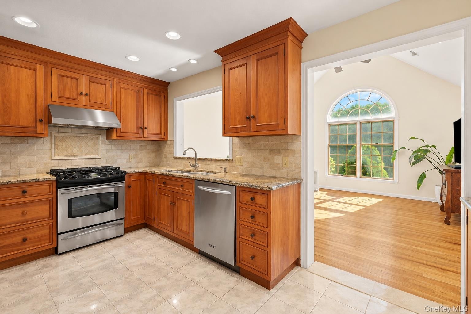 Kitchen includes stainless steel appliances and stone backsplash