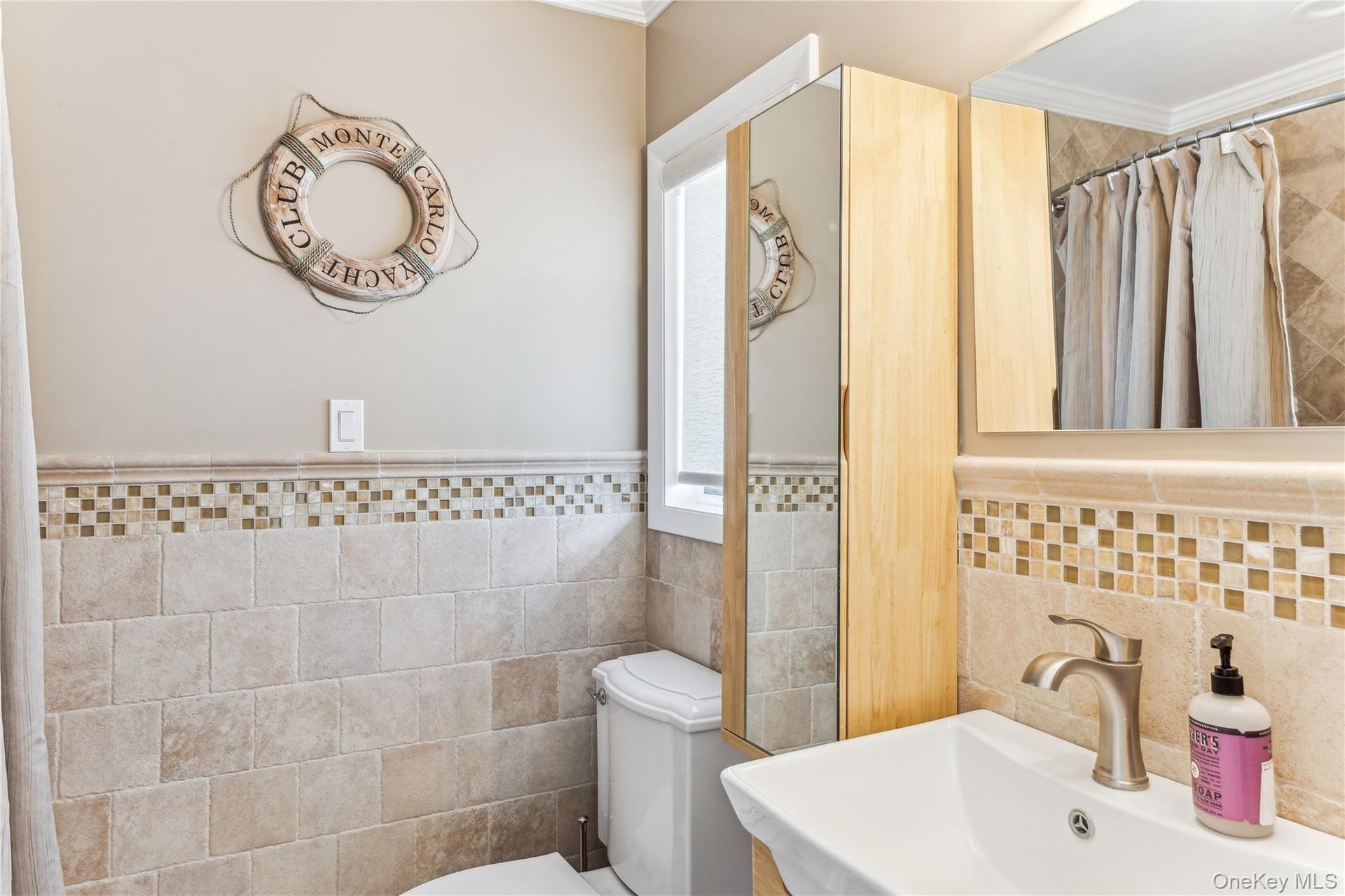 Bathroom featuring sink, tile walls, toilet, crown molding, and a shower with shower curtain