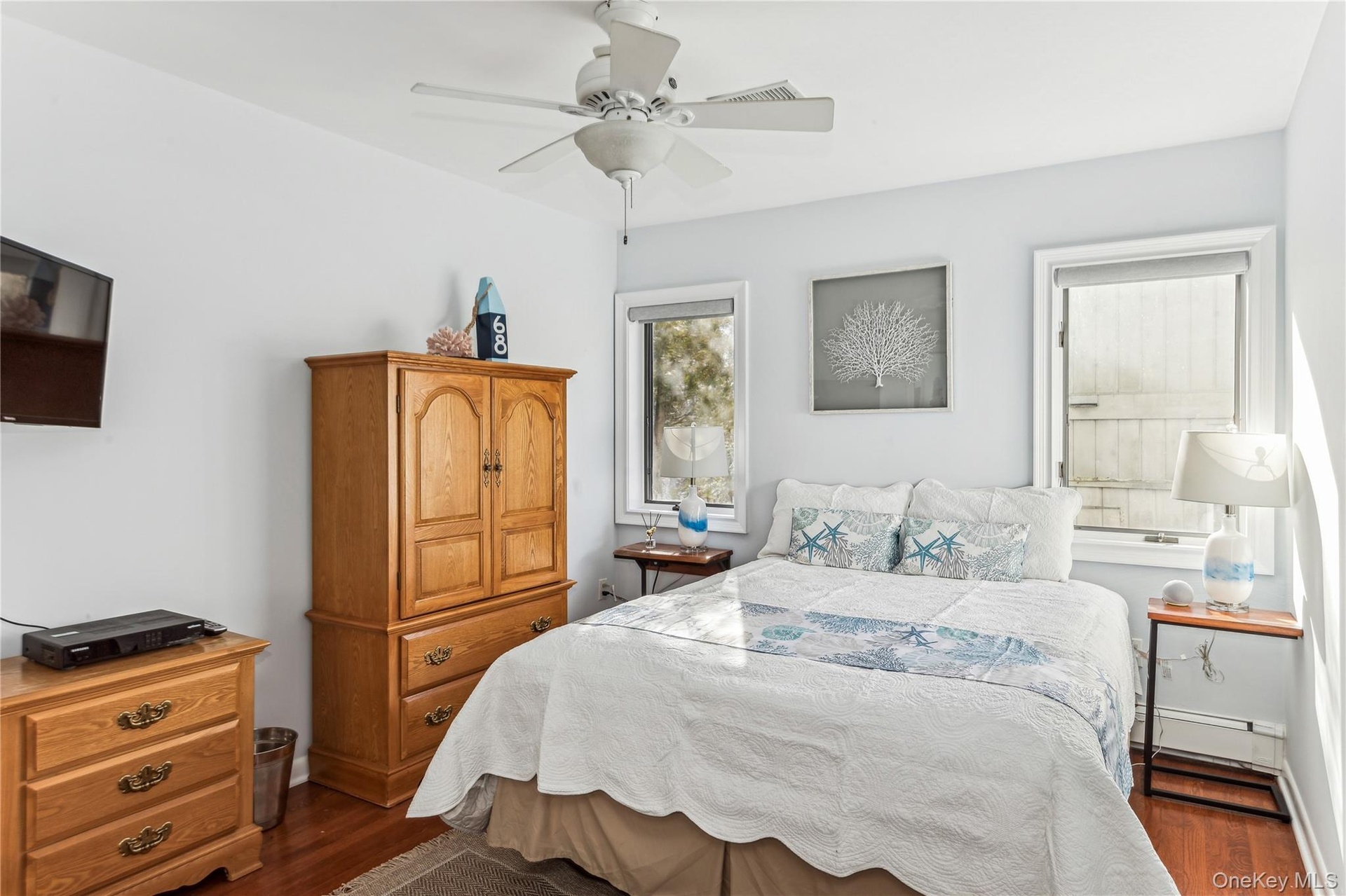 Bedroom featuring dark hardwood / wood-style flooring, a baseboard heating unit, and ceiling fan