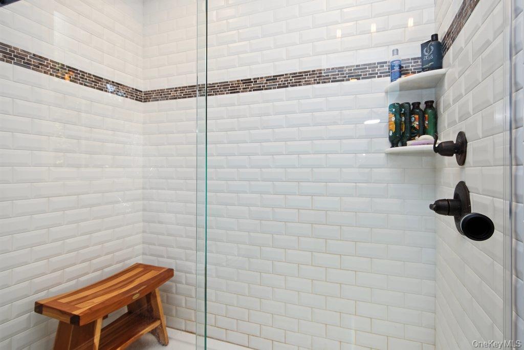White subway tile shower with a mosaic tile accent band, integrated corner shelving, and oil-rubbed bronze fixtures