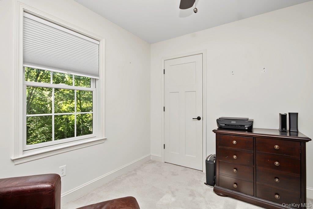 Double-hung window with white trim, white paneled door with black hardware, and light-colored carpeting