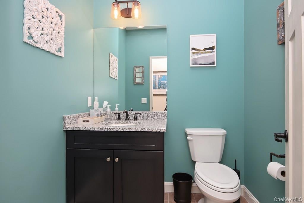 Bathroom featuring a dark wood-finish vanity with a light speckled countertop, dual-handle faucet, and a wall-mounted mirror
