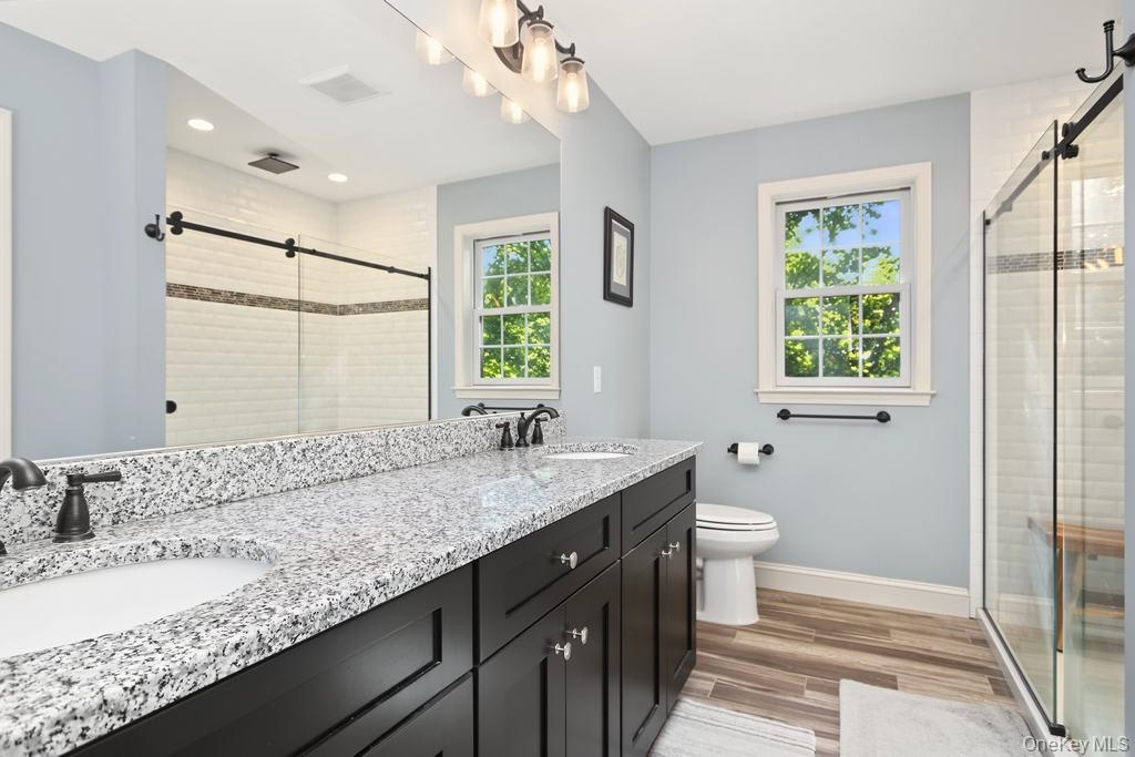 Dual vanity with speckled countertop and dark wood-finish cabinetry