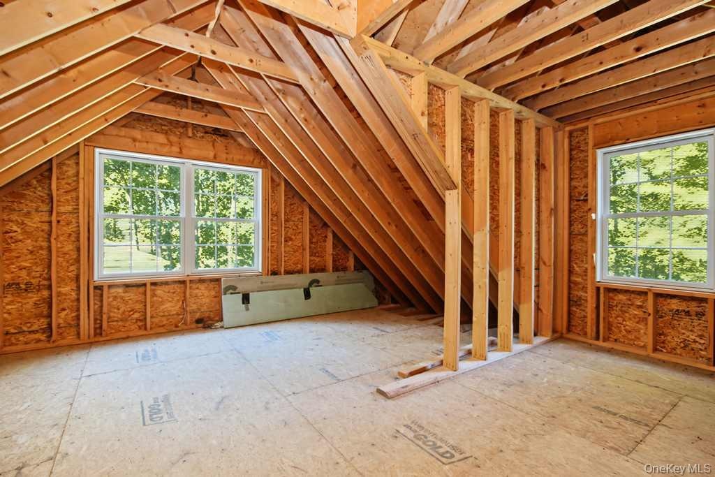 Unfinished attic space with exposed wood framing, two new windows, and oriented strand board flooring
