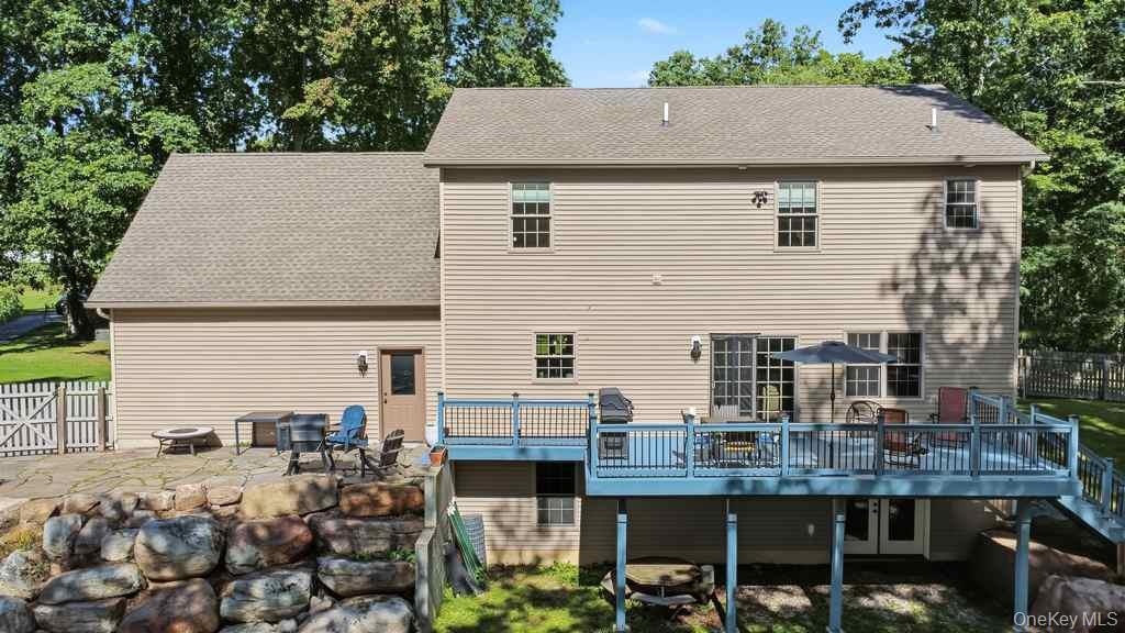 Large elevated rear deck with surrounding trees and a stone retaining wall