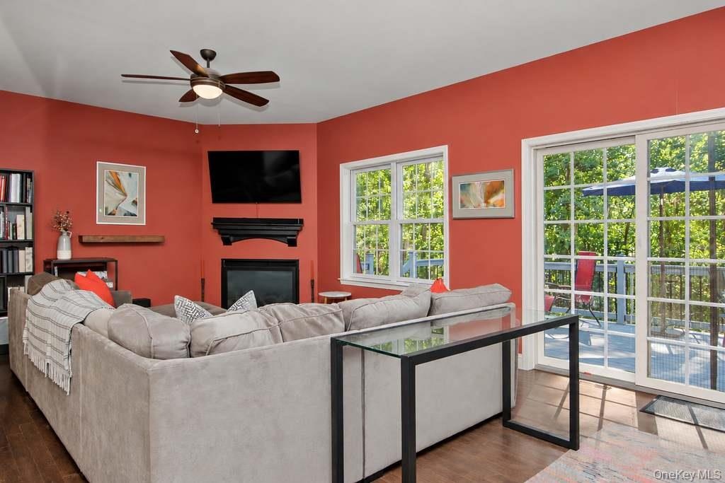 Corner fireplace with a mantel, wood-finish flooring, white-framed windows, and sliding glass doors to the exterior