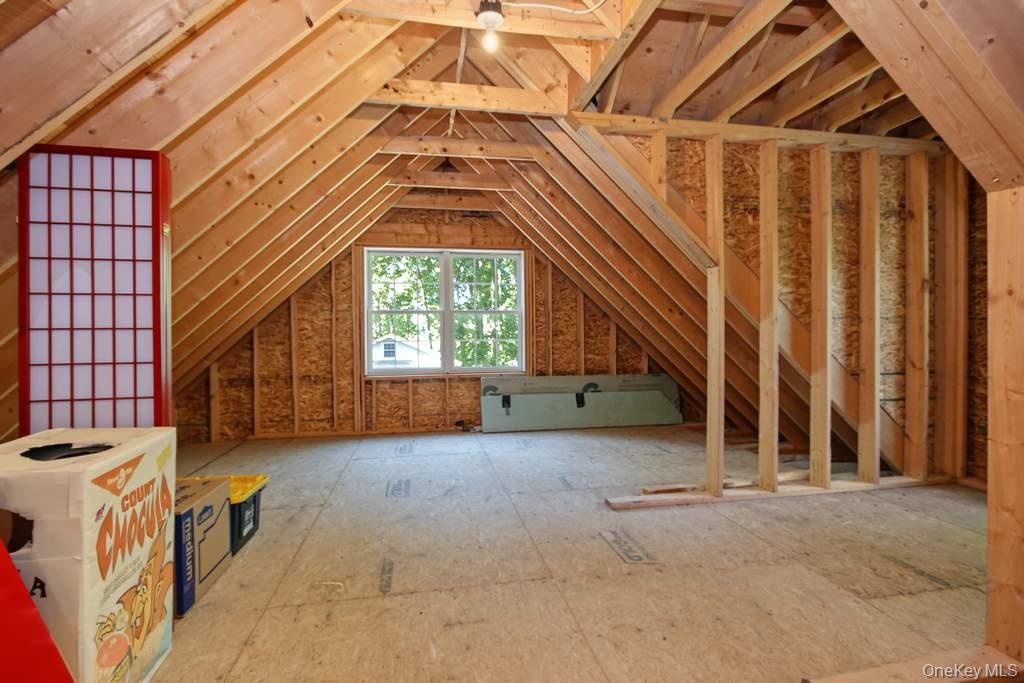 Exposed wood beam construction, unfinished flooring, window, and wood framing