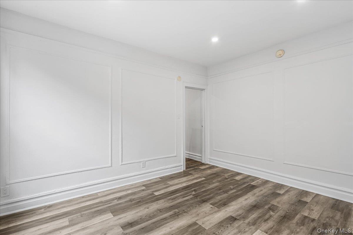 Empty room with a decorative wall, wood finished floors, and recessed lighting