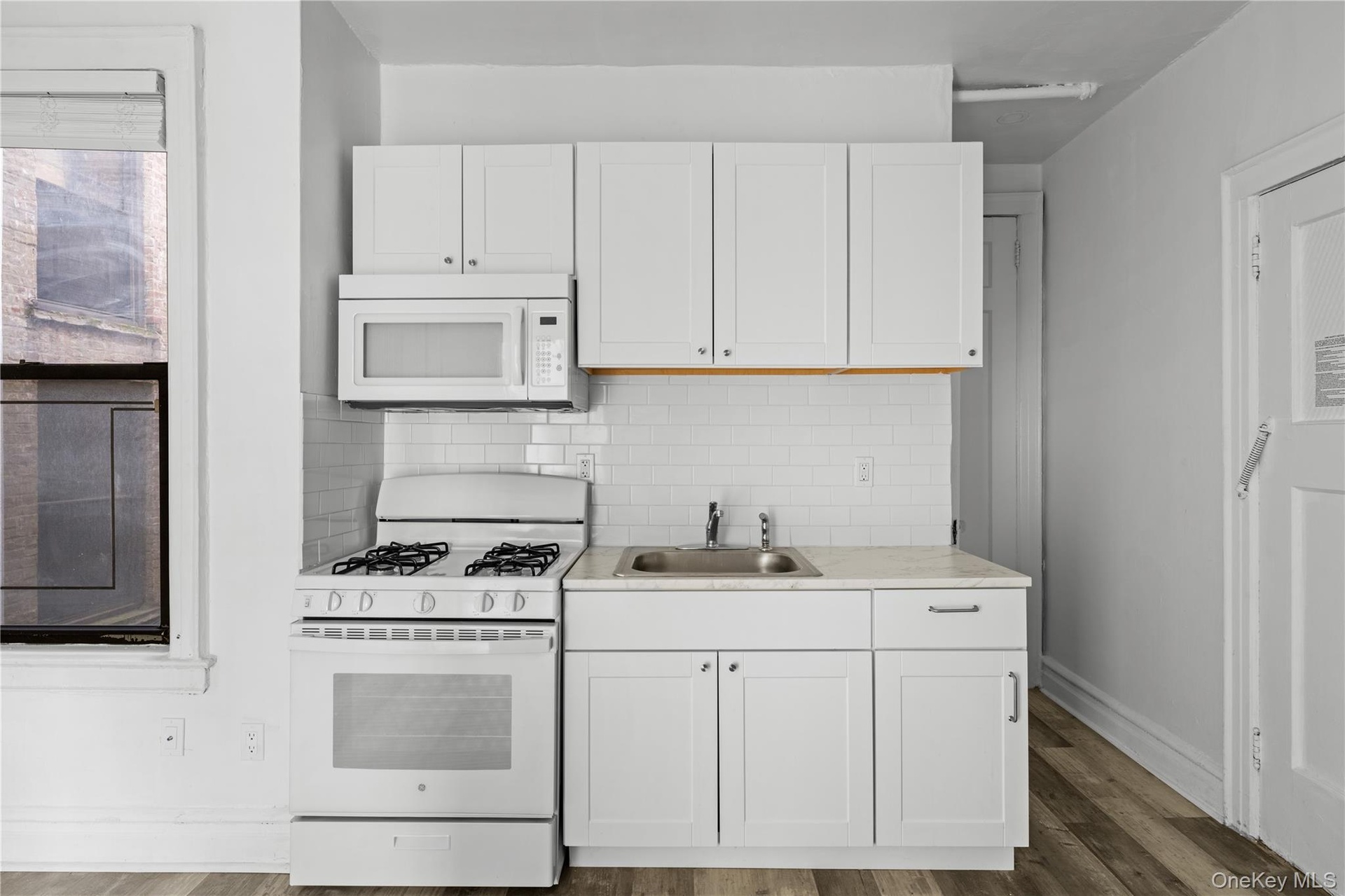 Kitchen featuring white appliances, white cabinetry, decorative backsplash, and dark wood-style floors