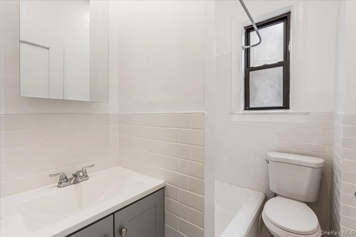 Bathroom featuring tile walls, vanity, wainscoting, and a shower