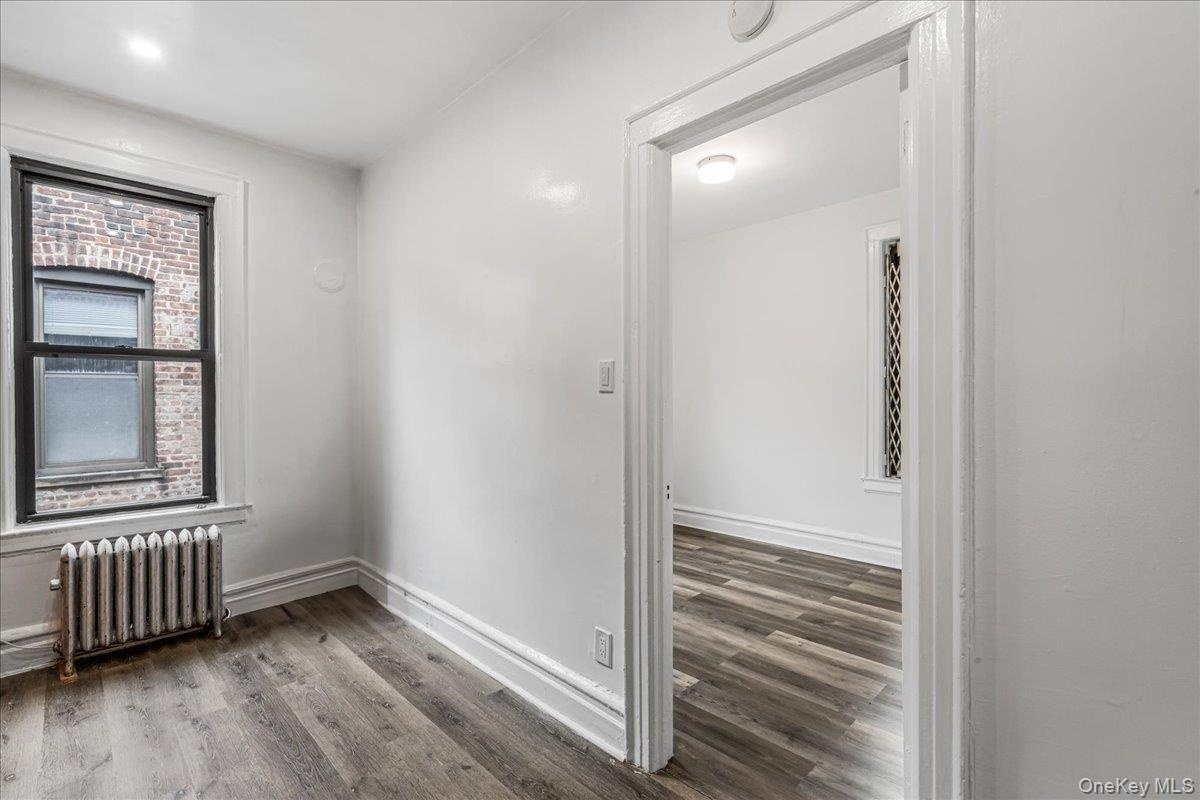 Unfurnished room featuring radiator and wood finished floors