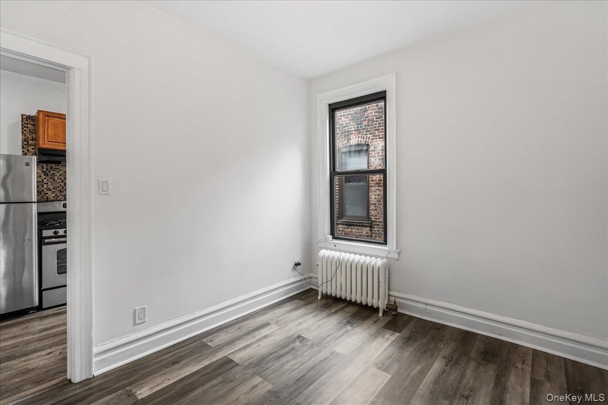 Unfurnished room featuring radiator and dark wood finished floors