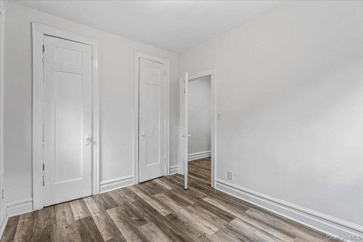 Unfurnished bedroom featuring wood finished floors and baseboards