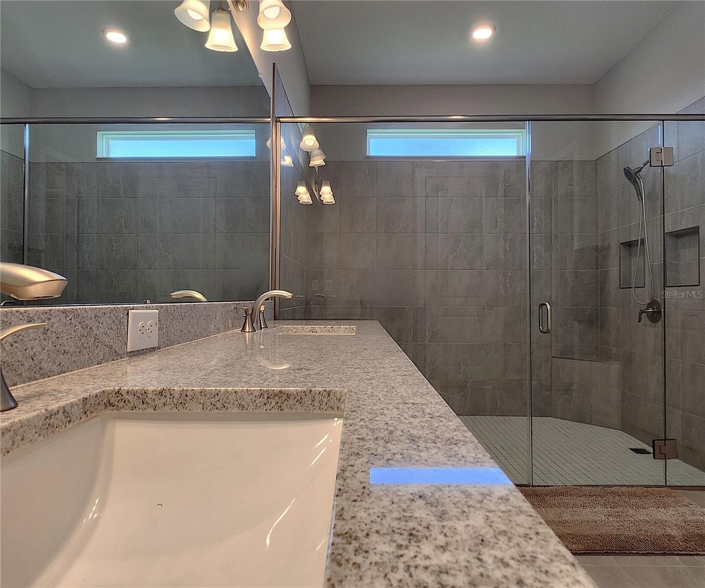 Master bathroom includes large walk-in  tiled shower, water closet, walk-in closet, dual sink vanity, granite countertops