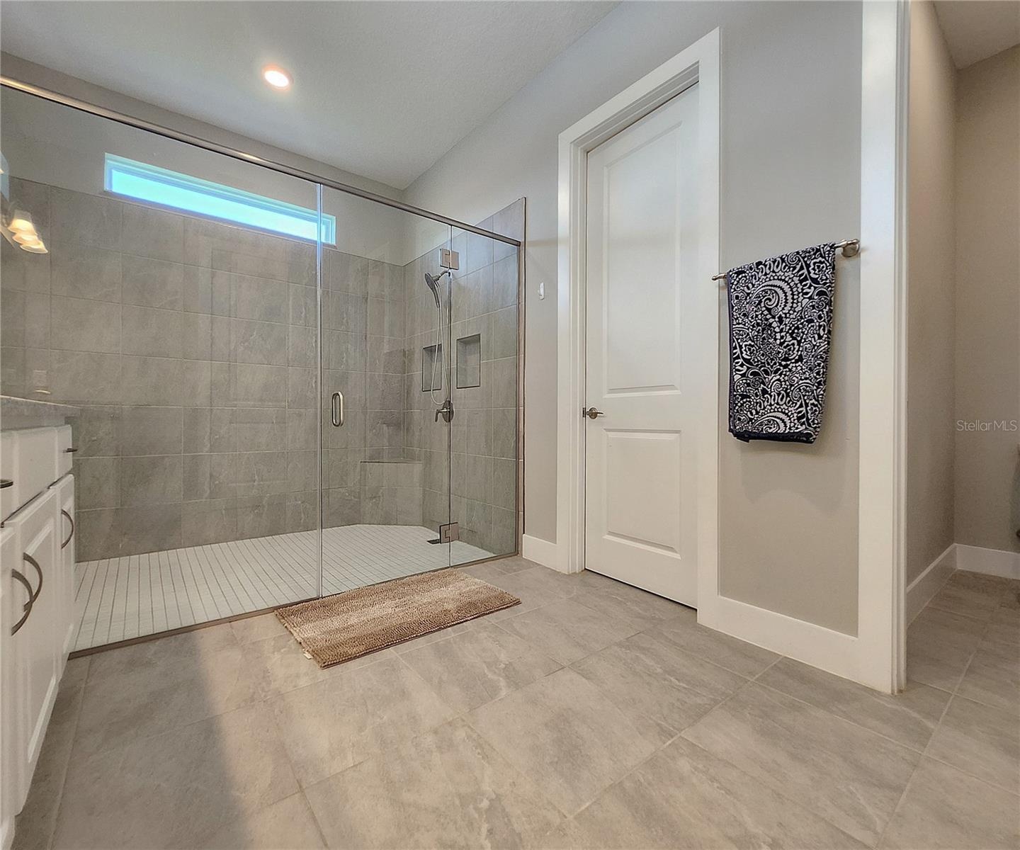 Master bathroom includes large walk-in  tiled shower, water closet, walk-in closet, dual sink vanity, granite countertops
