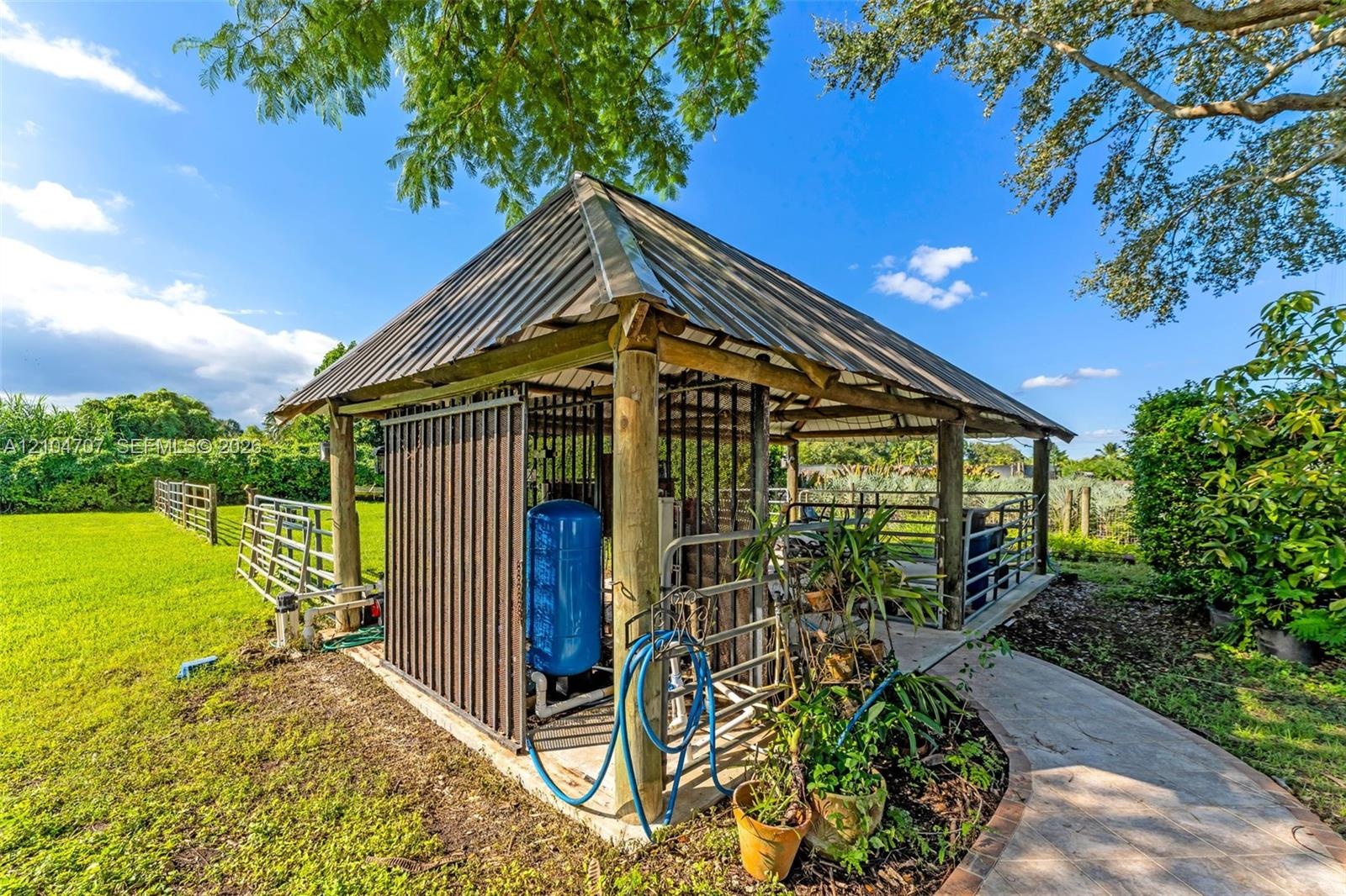 Expansive open-air lot featuring a grassy lawn, metal fencing, and perimeter hedging
