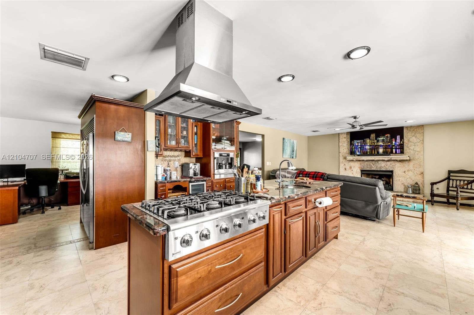 Spacious interior featuring neutral wall tones, large-format tile flooring, a multi-blade ceiling fan, and expansive windows with dark-finish frames