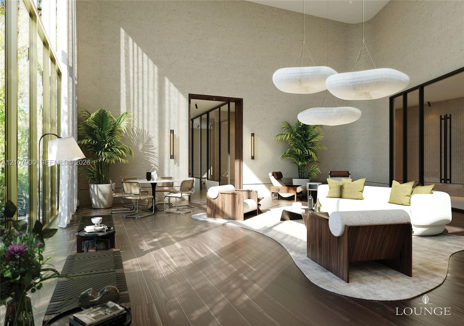 Expansive interior space featuring double-height ceilings, floor-to-ceiling windows with brass-tone frames, textured wall finishes, wide-plank wood-fi