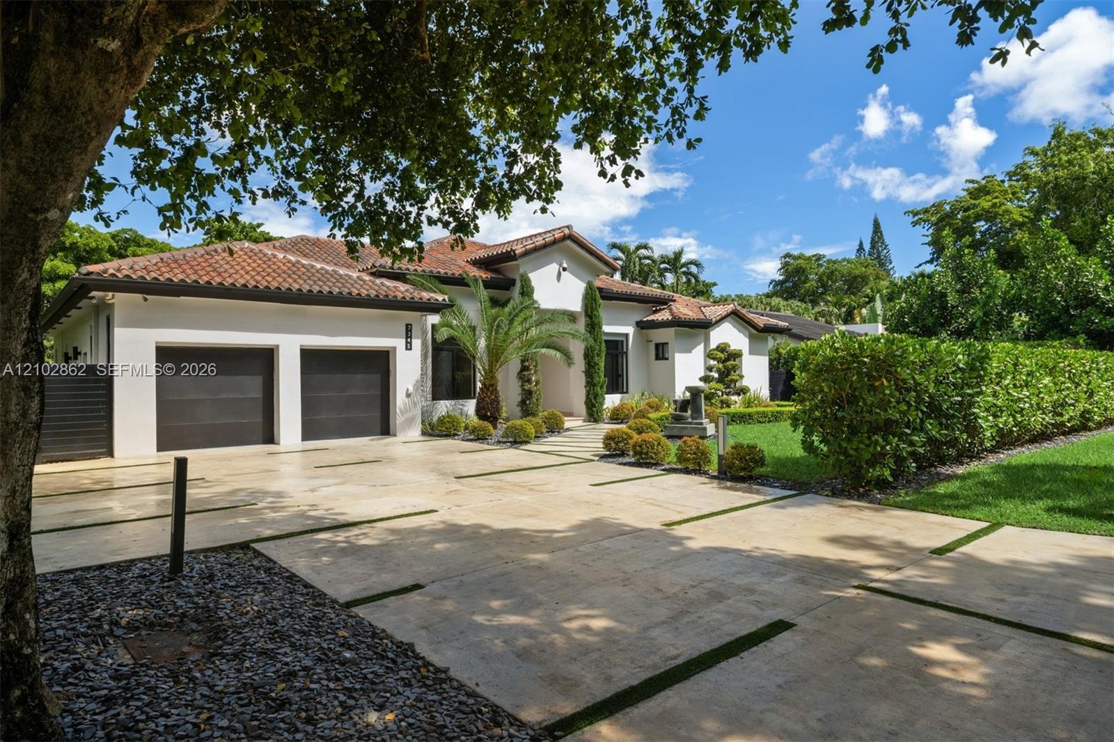 Single-story residence featuring a stucco exterior, clay tile roof, attached two-car garage, and a paver driveway with integrated turf strips